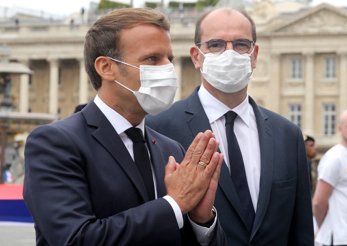 French President Emmanuel Macron (L) wearing a protective facemask greets guests flanked by French Prime Minister Jean Castex at the end of the annual Bastille Day military ceremony on the Place de la Concorde in Paris, on July 14, 2020. (AFP)