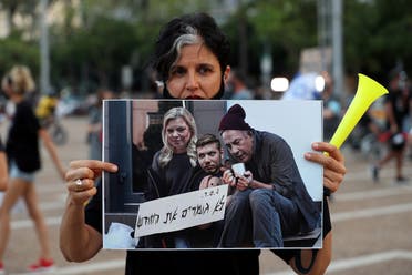 An Israeli woman holds a manipulated photo during a protest against the government’s response to the financial fallout of the coronavirus at Rabin square in Tel Aviv, Israel July 11, 2020. (Reuters)
