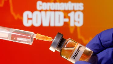 FILE PHOTO: A small bottle labeled with a Vaccine sticker is held near a medical syringe in front of displayed Coronavirus COVID-19 words in this illustration taken April 10, 2020. REUTERS/Dado Ruvic//File Photo