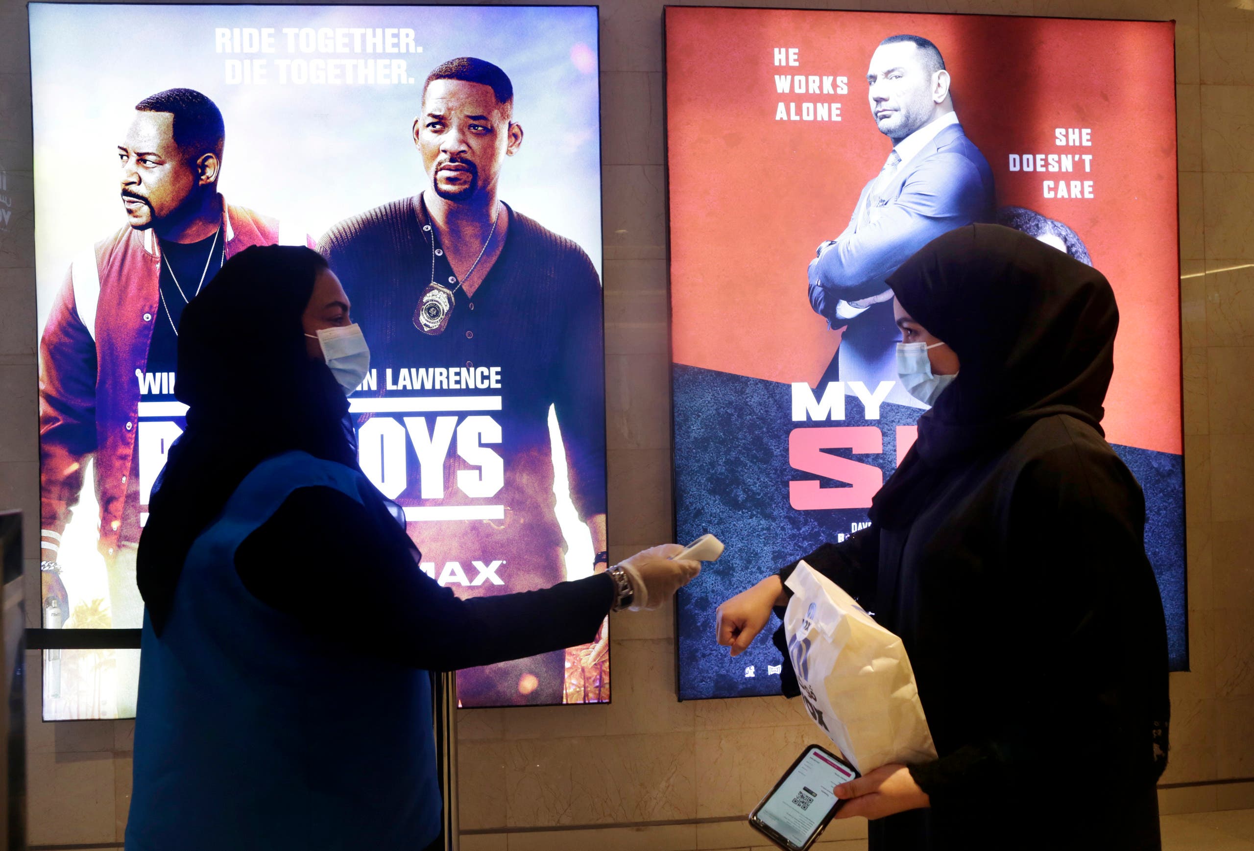 A Saudi movie viewer has her temperature taken as she wears a face mask to help curb the spread of the coronavirus, at VOX Cinema hall in Jiddah, Saudi Arabia, Friday, June 26, 2020, after the announcement of easing of lockdown measures amid the coronavirus outbreak. (AP Photo/Amr Nabil)