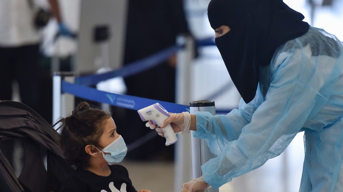 A Saudi health worker takes the temperature of a child at terminal 5 in the King Fahad International Airport, designated for domestic flights, in the capital Riyadh on May 31, 2020, after authorities lifted the ban on flights within the country.