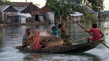 Women and children use a boat to make their way through floodwaters in Sunamganj on July 15, 2020. (AFP)