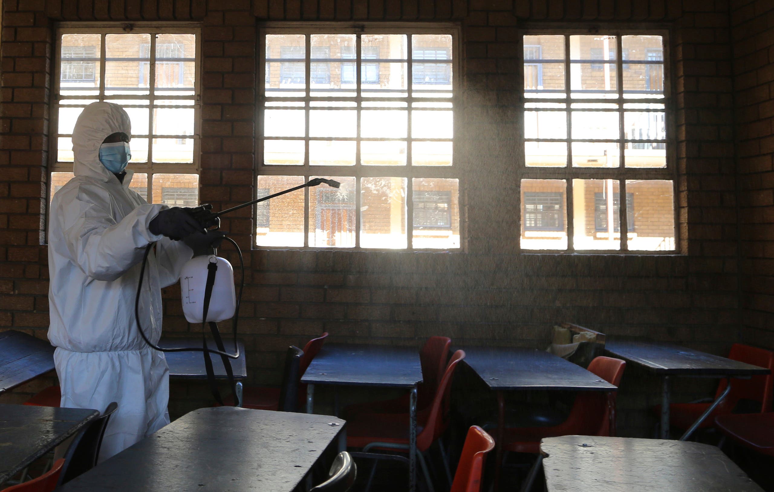 In this May 26, 2020, a worker from Bidvest Prestige wearing personal protective equipment, sprays disinfectant in a classroom to help reduce the spread the coronavirus ahead of the reopening of Landulwazi Comprehensive School, east of Johannesburg, South Africa. (AP)