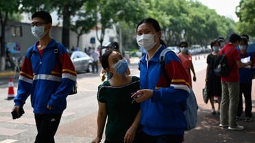 A mask-clad student arrives with a family member before entering her school in Beijing on July 8, 2020. (AFP)