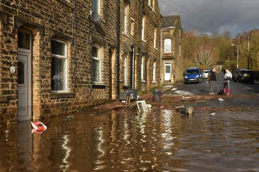 People stand near debris caused by flooding in a street in Mytholmroyd, northern England, on February 9, 2020, after the River Calder burst its banks as Storm Ciara swept over the country. (AFP)