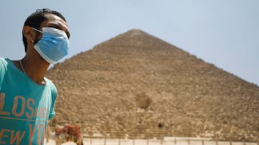 A man wearing a face mask is seen in front of the Great Pyramids of Giza after reopening for tourist visits, following the outbreak of the coronavirus disease (COVID-19), in Cairo, Egypt July 1, 2020. REUTERS/Mohamed Abd El Ghany