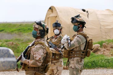 Iraqi soldiers wear protective face masks, following the outbreak of coronavirus disease (COVID-19), as they stand guard during the hand over of Qayyarah Airfield West from US-led coalition forces to Iraqi Security Forces, in the south of Mosul, Iraq March 26, 2020. (Reuters)