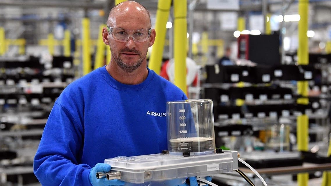 An Airbus employee poses with a completed unit from the assembly line to produce ventilators at the Advanced Manufacturing Research Centre (AMRC Cymru) in Broughton, north Wales on April 30, 2020. (Reuters)