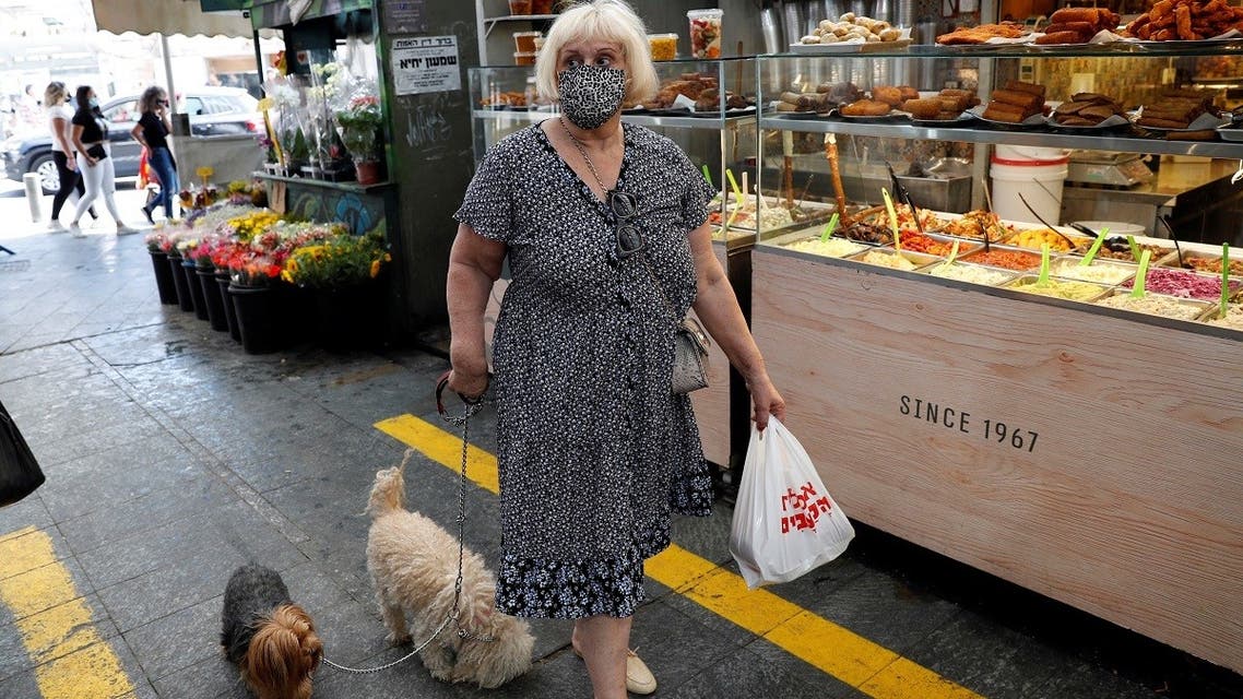 A woman wears a face mask as she walks with her dogs in a main market in Jerusalem on July 16, 2020. (Reuters)2020-07-17T042242Z_1193398852_RC2SUH9W4TFT_RTRMADP_3_HEALTH-CORONAVIRUS-ISRAEL