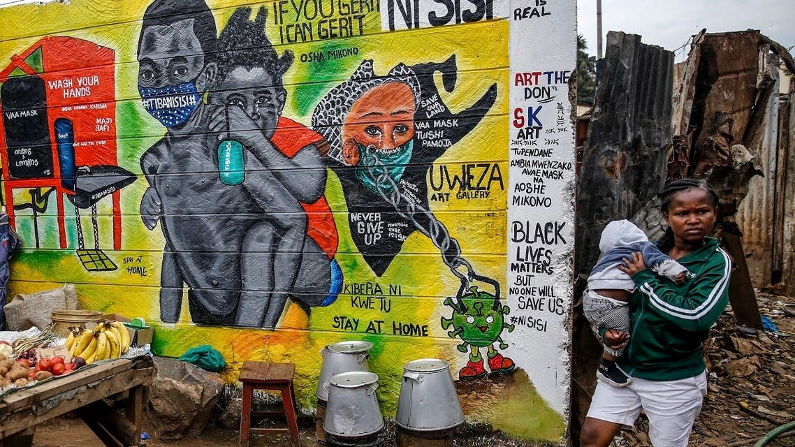 A woman carries a baby past an informational mural warning people about the dangers of the new coronavirus and how to prevent transmission, with words in Swahili reading We are the Cure, painted by youth artists from the Uweza Foundation, in the Kibera slum, or informal settlement, of Nairobi, Kenya Wednesday, July 8, 2020. (AP)