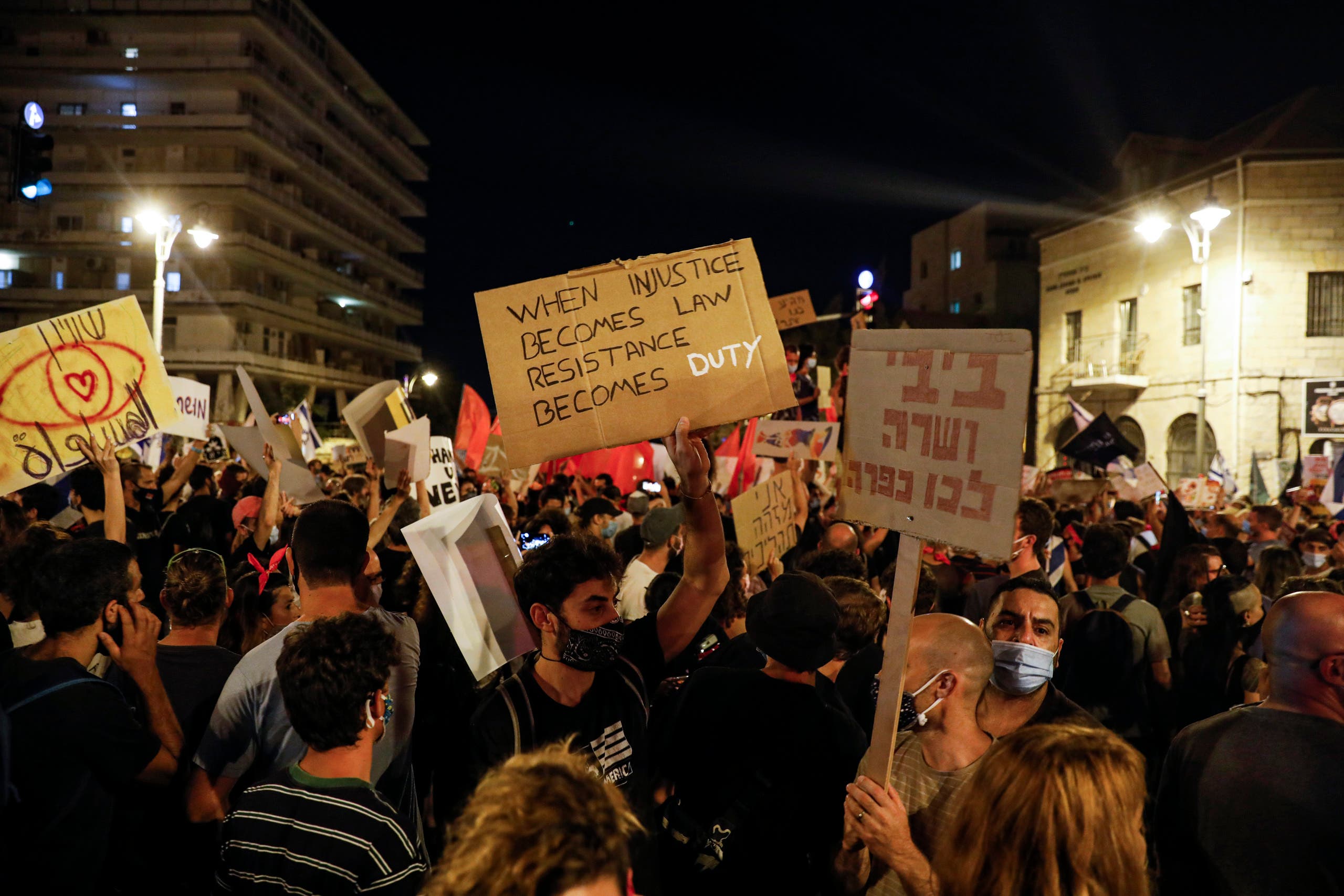 Protesters, clad in masks due to the COVID-19 coronavirus pandemic, gather for a demonstration against the Israeli government near the Prime Minister's residence in Jerusalem. (AFP)