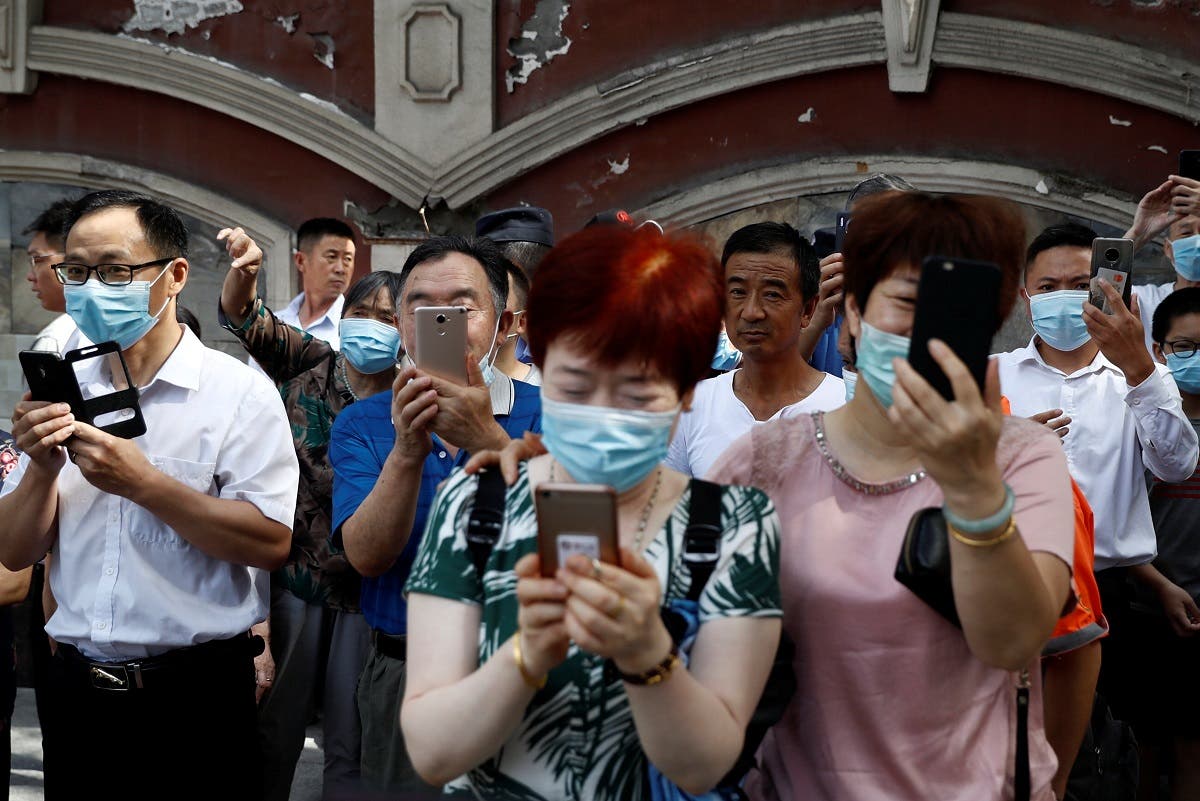 People take pictures of a bus, which US Consulate staff loaded up in the morning, as it leaves the US Consulate General in Chengdu, Sichuan province, China, on July 26, 2020. (Reuters)