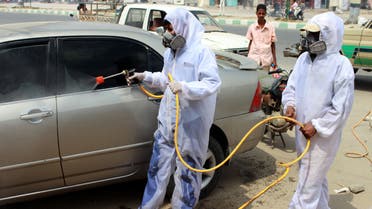 Yemeni sanitation workers, wearing protective gear, spray disinfectant in a neighbourhood in the northern Hajjah province on May 31, 2020, during the ongoing coronavirus pandemic. 