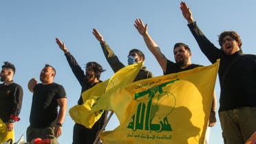 Supporters of the Lebanese Shiite movement Hezbollah perform a salute as they stand behind motorcycles carrying the group's flags in the southern Lebanese district of Marjayoun on the border with Israel on May 25, 2020. Twenty years after the withdrawal of Israeli forces from Lebanon, Hezbollah still enjoys wide support among youth regaled with tales of the Shiite group ending 22 years of Israeli occupation.
