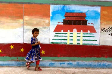 A Uighur child walks past a mural depicting China's Tiananmen Gate in western China's Xinjiang province on July 17, 2014. (AP)