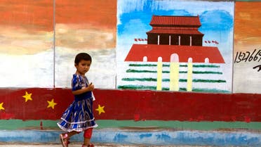 A Uighur child walks past a mural depicting China's Tiananmen Gate on the streets of Aksu in western China's Xinjiang province. (File Photo: AP)