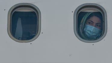 A woman form a group of 85 vulnerable refugees, mainly families with children with health problems, looks on from the windows of a plane after boarding for Germany as part of the EU relocation program from Greek islands' hotspots on July 24, 2020 at Athens' international airport in Spata. (AFP)