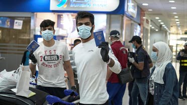 Kuwaiti boys wearing protective face masks and quarantine tracking bracelets, following the outbreak of the coronavirus, pose for the camera as they hold up their passports in Kuwait Airport, April 21, 2020. (Reuters)