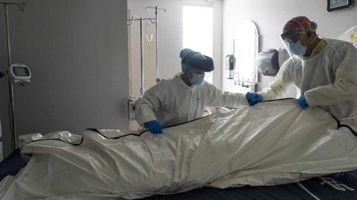 Medical staff wearing full PPE wrap a deceased patient with bed sheets and a body bag in the COVID-19 intensive care unit at the United Memorial Medical Center on June 30, 2020 in Houston, Texas. (AFP)