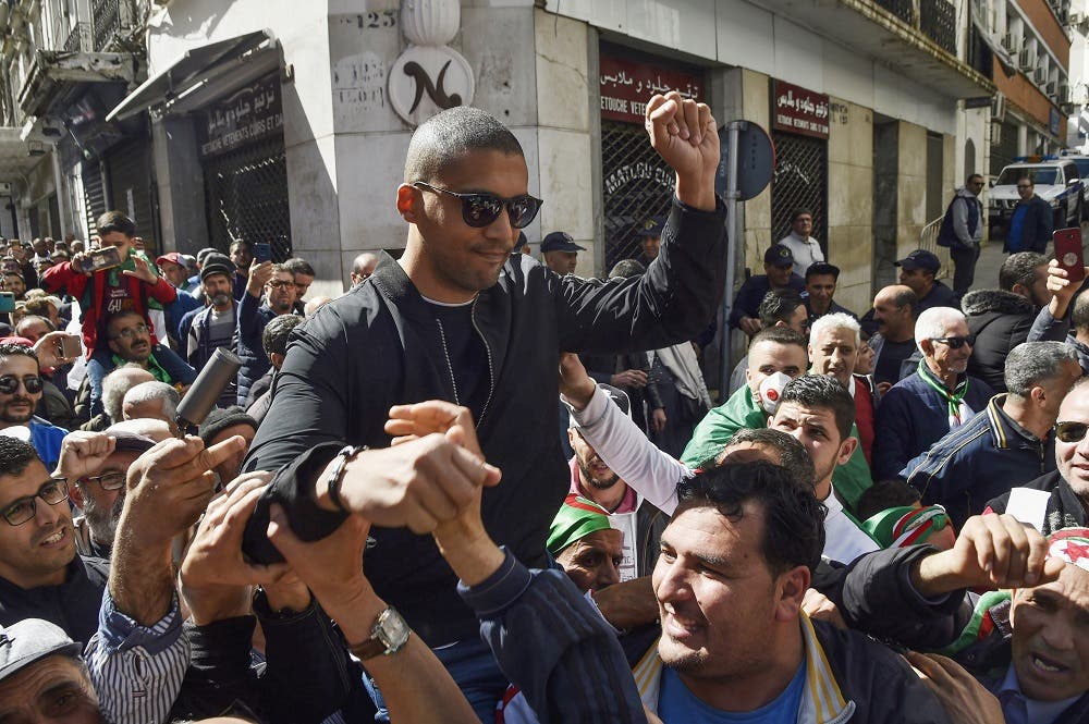 A picture taken on March 6, 2020 shows Algerian protesters carrying journalist Khaled Drareni on their shoulders. (AFP)