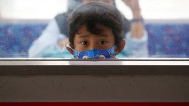 A child wearing a protective mask looks through a window while traveling with a commuter train, following the coronavirus disease (COVID-19) outbreak in Jakarta. (Reuters)