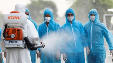 A health worker in a white protective suit sprays disinfectant at Vietnamese construction workers infected with the coronavirus disease (COVID-19), upon their arrival at the tropical diseases hospital after being repatriated from Equatorial Guinea via a specially-adapted Vietnam Airlines plane filled with medical equipment and negative pressure chambers, in Hanoi, Vietnam July 29, 2020. REUTERS/Kham