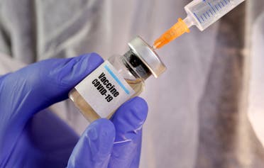 A woman holds a small bottle labeled with a Vaccine COVID-19 sticker and a medical syringe in this illustration. (Reuters)