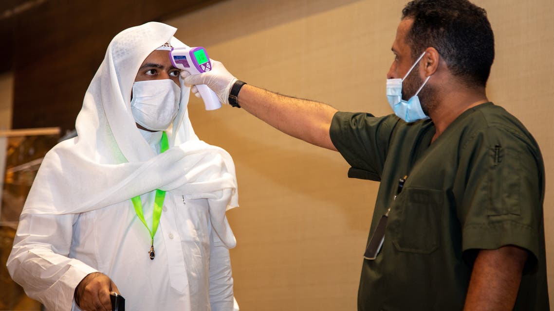 A handout picture provided by the Saudi Ministry of Hajj and Umra on July 25, 2020, shows a medical worker, mask-clad due to the COVID-19 coronavirus pandemic, checking the body temperature of travellers arriving for the annual Hajj pilgrimage at a hotel in Saudi Arabia's holy city of Mecca. The 2020 hajj season, which has been scaled back dramatically to include only around 1,000 Muslim pilgrims as Saudi Arabia battles a coronavirus surge, is set to begin on July 29. Some 2.5 million people from all over the world usually participate in the ritual that takes place over several days, centred on the holy city of Mecca. This year's hajj will be held under strict hygiene protocols, with access limited to pilgrims under 65 years old and without any chronic illnesses.
