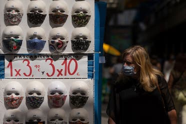 A woman wearing a face mask walks past a display of masks on sale at a shop in the center of Madrid on July 29, 2020. (AFP)