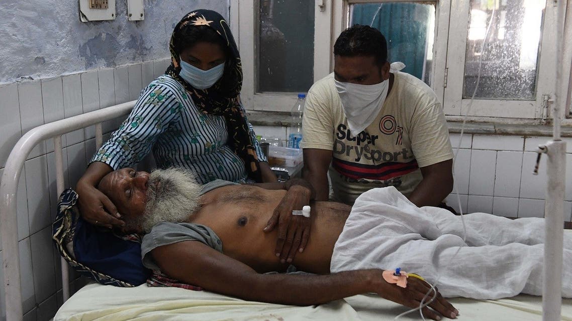 Relatives sit near the patient Sawinder Singh, who is treat at a civil hospital after allegedly drinking spurious alcohol, at Tarn Taran, about 25 km from Amritsar on August 1, 2020. (AFP)