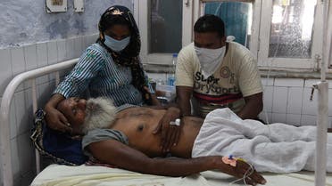 Relatives sit near the patient Sawinder Singh, who is treat at a civil hospital after allegedly drinking spurious alcohol, at Tarn Taran, about 25 km from Amritsar on August 1, 2020. (AFP)