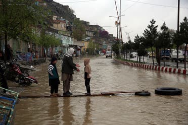 An Afghan man walks with his children through floodwaters as heavy rain falls in Kabul, Afghanistan, Tuesday, April 16, 2019. (AP)