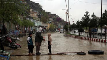 An Afghan man walks with his children through floodwaters as heavy rain falls in Kabul, Afghanistan, Tuesday, April 16, 2019. (AP)