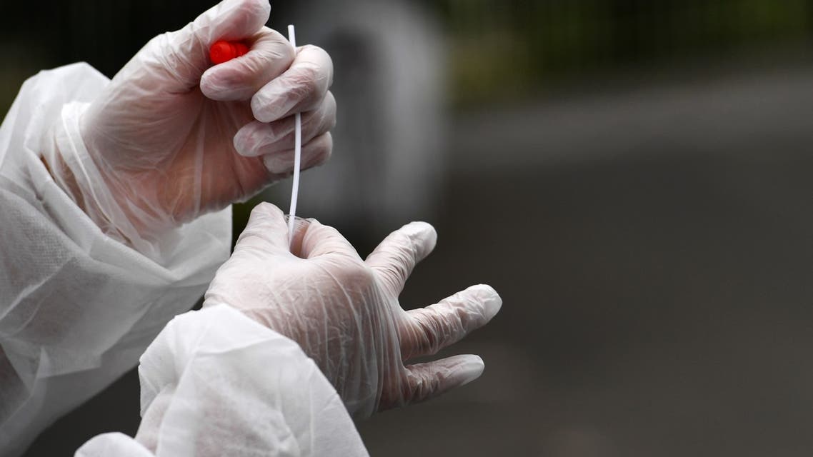 A medical staff holds a nasal swab as he collects samples from a person at a COVID-19 (the novel coronavirus) drive-in test in Brest, western France, on July 31, 2020. 