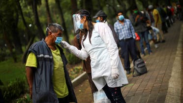 A medical staff scans the temperature of a man lining up for free food at a public park, as the outbreak of the coronavirus disease (COVID-19) continues in Mexico City, Mexico, July 30, 2020. REUTERS/Edgard Garrido