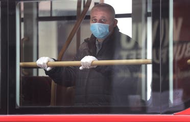 A man wears a mask to protect against the coronavirus as he looks out of the window of a bus in London on May 4, 2020. (AP)