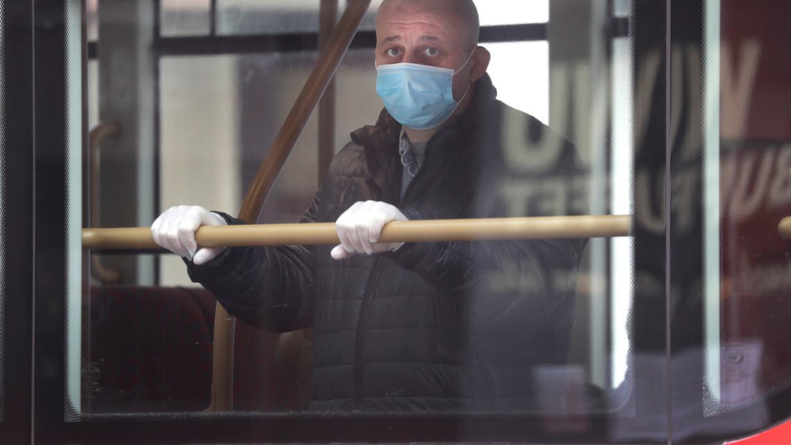A man wears a mask to protect against the coronavirus as he looks out of the window of a bus in London on May 4, 2020. (AP)