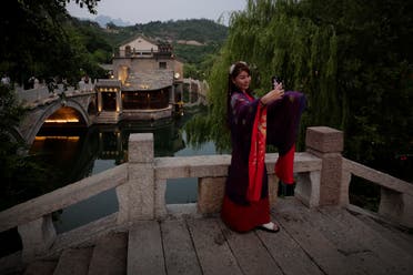 A woman wearing traditional clothing takes a selfie at the ancient village in Gubei Water Town, a popular tourist spot in Beijing, Tuesday, June 9, 2020. (AP)