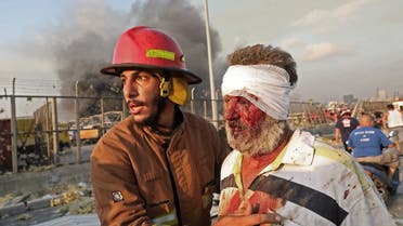 A wounded man is helped by a fireman near the scene of an explosion in Beirut on August 4, 2020. (AFP)