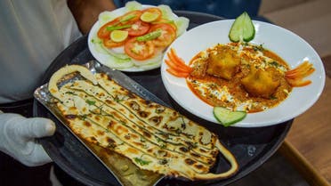 A waiter carries 'Covid Curry' and 'Mask Naan,' two Covid-19 coronavirus-themed dishes, to serve to customers at their restaurant in Jodhpur on August 3, 2020. (AFP)