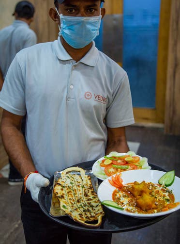 A waiter carries 'Covid Curry' and 'Mask Naan,' to serve to customers at their restaurant in Jodhpur on August 3, 2020. (AFP)