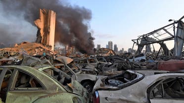 Damaged cars are pictured in front of billowing smoke behind the grain silos at the port of Beirut following a massive explosion that hit the heart of the Lebanese capital on August 4, 2020. (AFP)