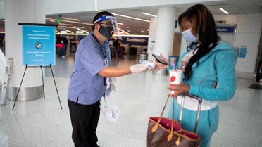 Airport employee hands out a face masks to an airline passenger at LAX airport, amid the coronavirus pandemic, in Los Angeles, California, US, August 4, 2020. (Reuters)
