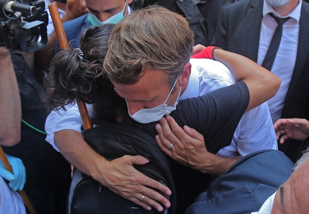 A Lebanese youth hugs French President Emmanuel Macron during a visit to the Gemmayzeh neighbourhood, which has suffered extensive damage due to a massive explosion in the Lebanese capital, on August 6, 2020. (AFP)