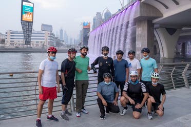 Sheikh Mohammed and associates get down from their bikes for a group photo at Dubai Canal. (Dubai Media Office)