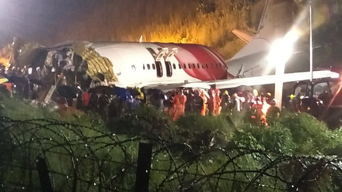First responders gather around the wreckage of an Air India Express jet, which was carrying more than 190 passengers and crew from Dubai, after it crashed by overshooting the runway at Calicut International Airport in Karipur, Kerala, India, on August 7, 2020. (AFP)