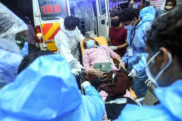 Health workers transfer an injured passenger on a stretcher to take her to a hospital in Kozhikode, Kerala, after the Air India Express crashed at Calicut International Airport, on August 7, 2020. (AFP)