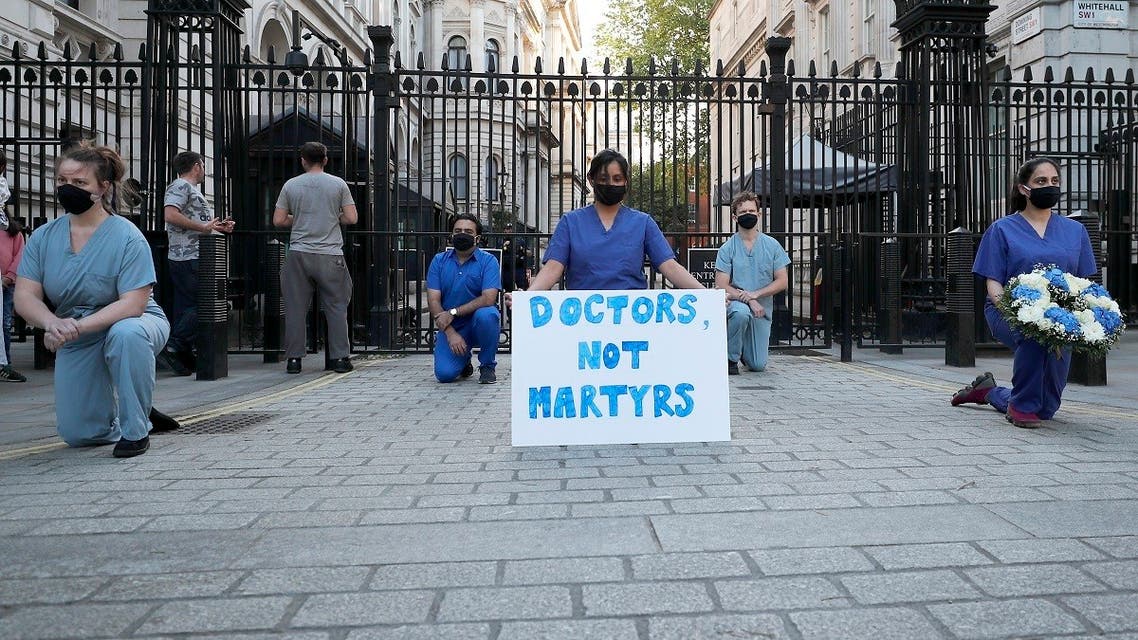 Doctors and nurses kneel in front of Downing Street ahead of the clap to remember colleagues who have died fighting the coronavirus pandemic in London. (AP)
