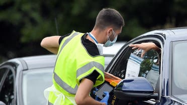 An official delivers a testing kit through a car window at a mobile drive through coronavirus disease (COVID-19) testing centre, in Richmond, London, Britain August 4, 2020. (Reuters)