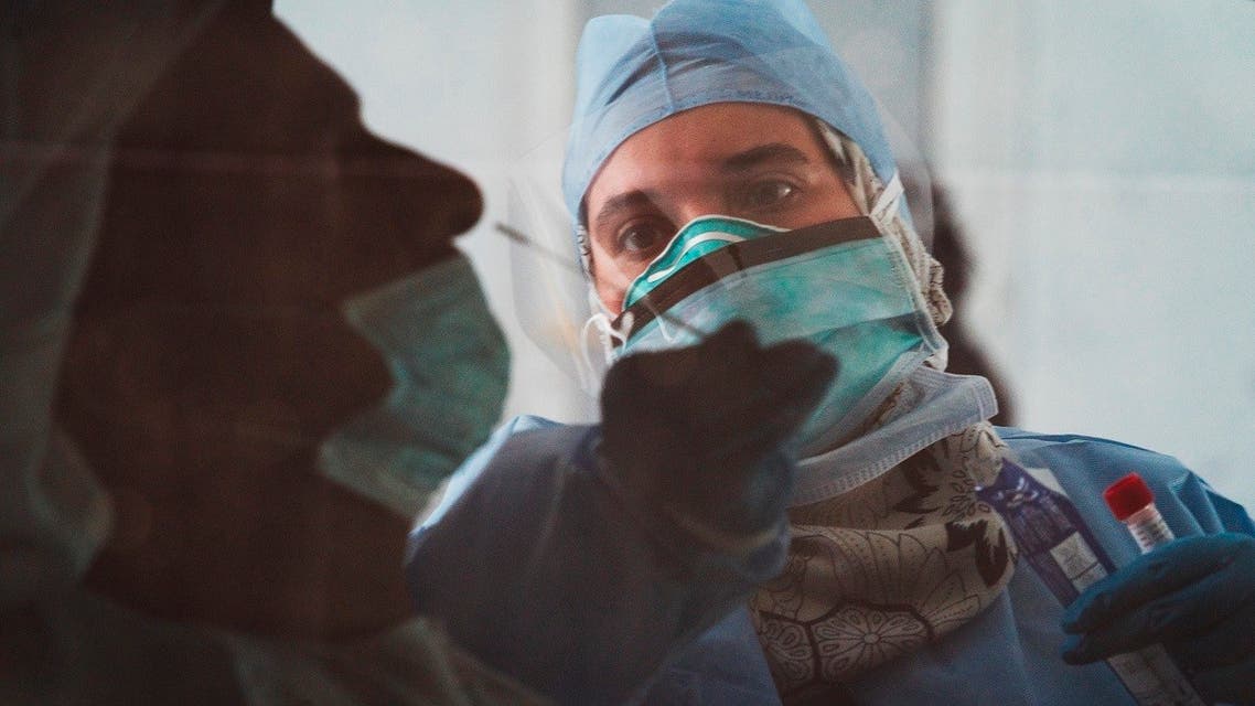 In this image taken through a tinted car window, a technician takes a nasal swab for a new coronavirus detection test at a drive-thru testing facility in Abu Dhabi. (AP)